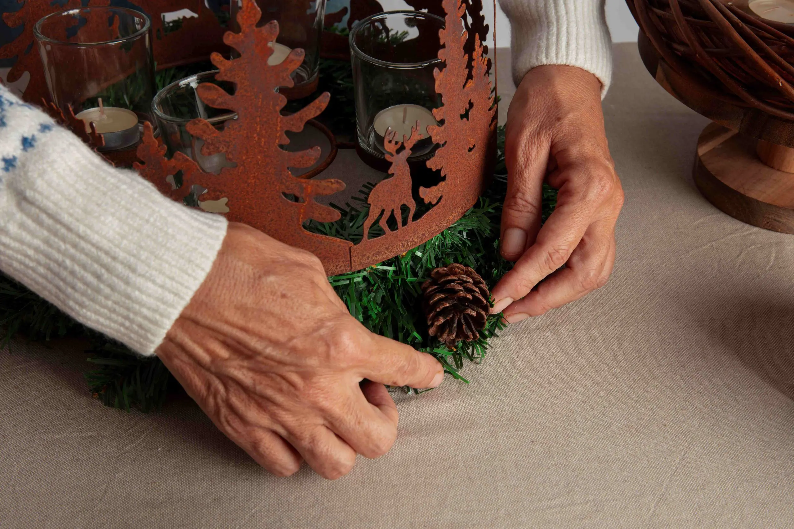 A woman's hands assembling holiday themed wreath