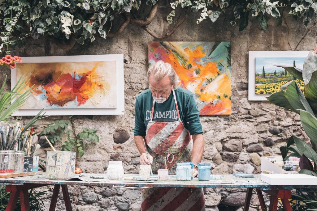 old white bearded man with apron sculpting and painting art therapy