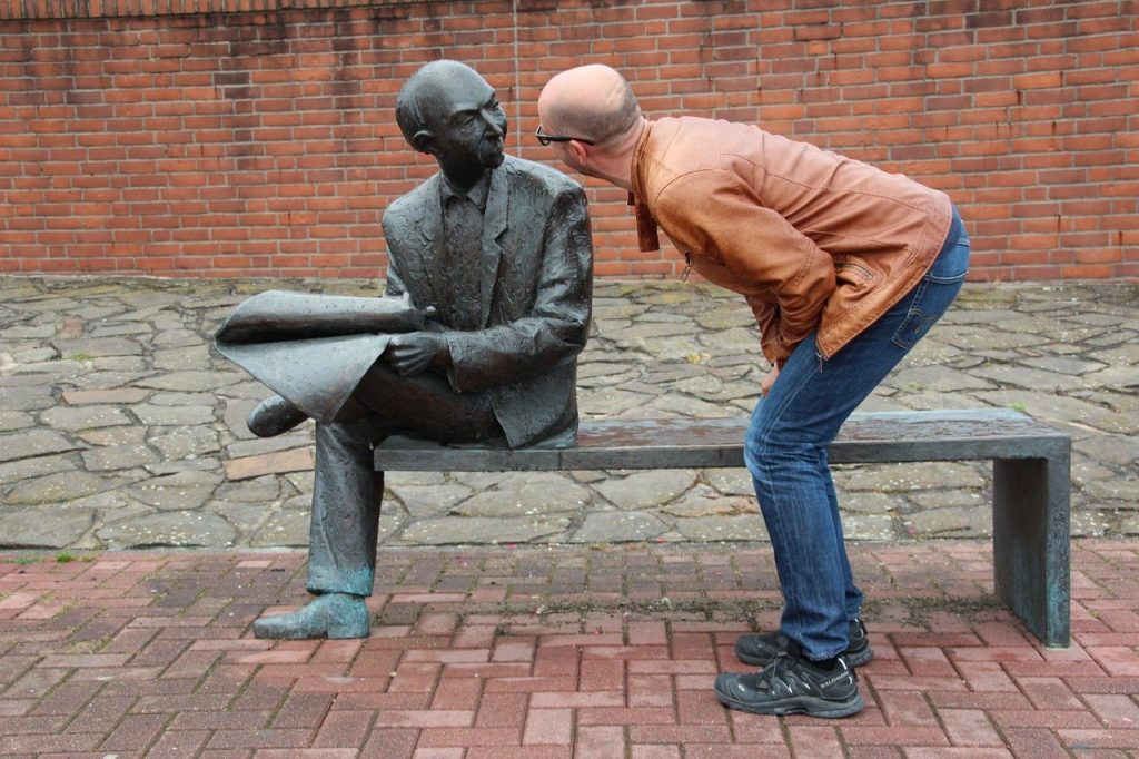 man crouching to look at a statue
