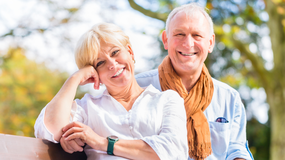 older couple smiling while sitting on a bench